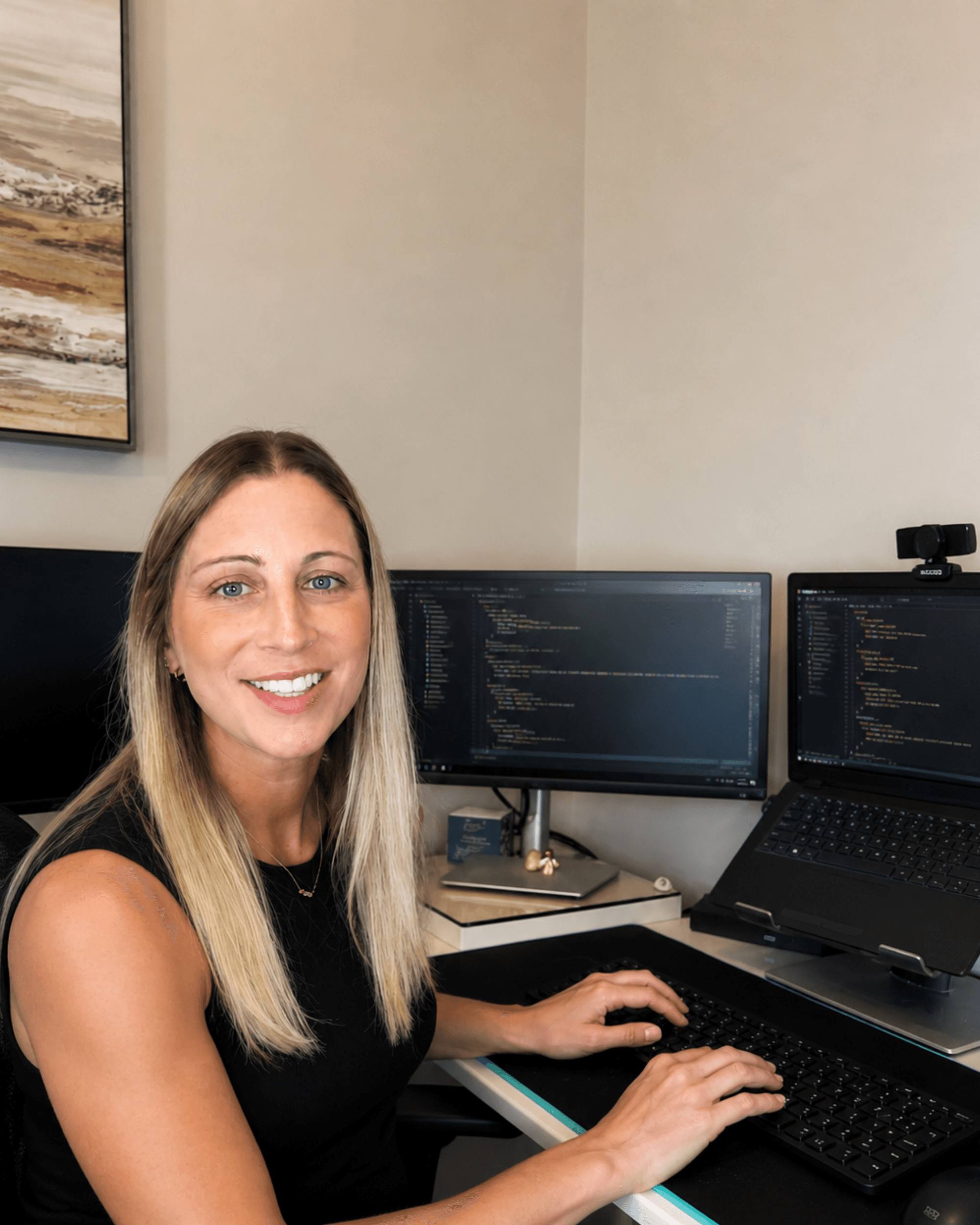 Chelsea coding at her desk with dual monitors